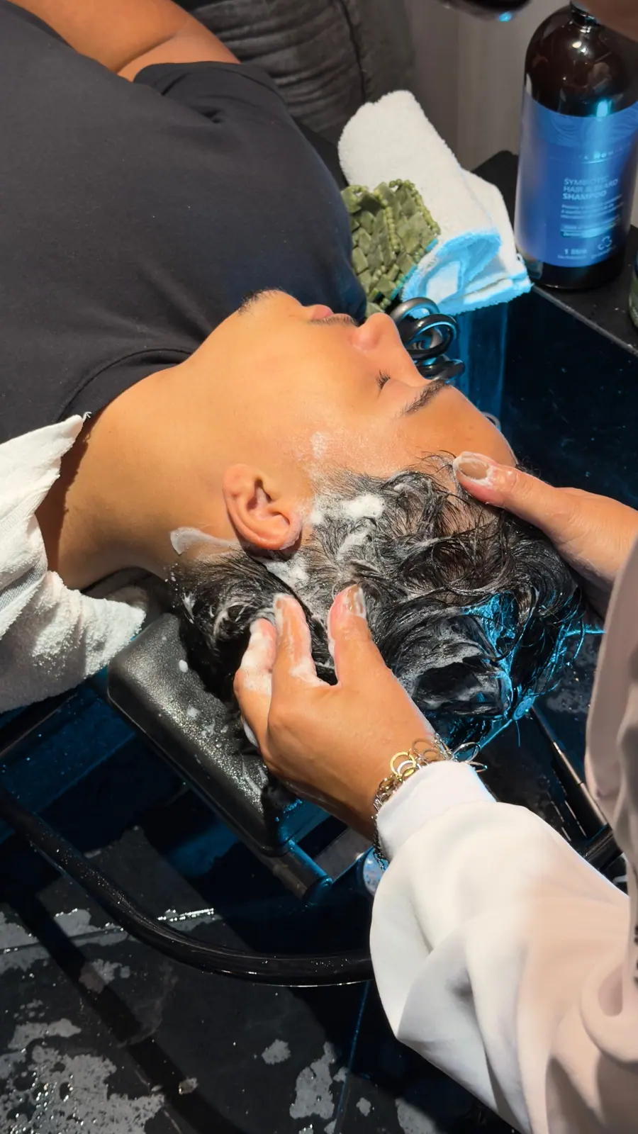 Mãos massageando o couro cabeludo com espuma, durante a lavagem terapêutica